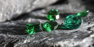 The glimmering natural green sapphire gemstones on a rugged rock surface