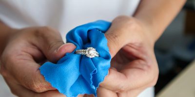 Jeweller hand polishing and cleaning jewelry diamond ring with micro fiber fabric